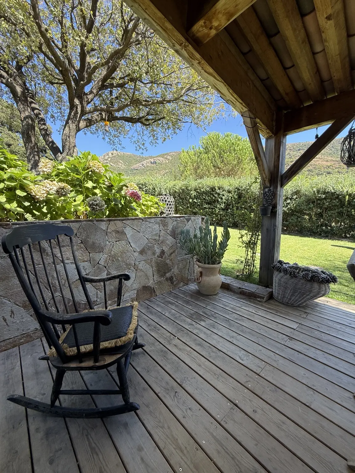 Terrasse en bois avec fauteuil à bascule ouverte sur le jardin